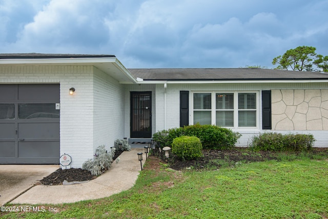 view of exterior entry featuring a lawn and a garage