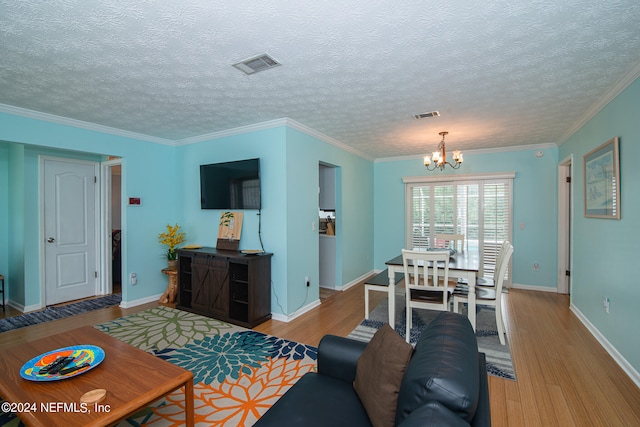 living room with ornamental molding, an inviting chandelier, light hardwood / wood-style floors, and a textured ceiling