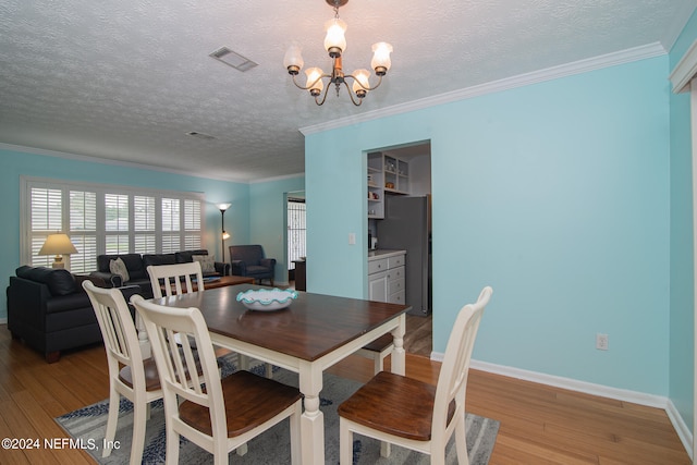 dining room featuring a textured ceiling, light hardwood / wood-style floors, and crown molding