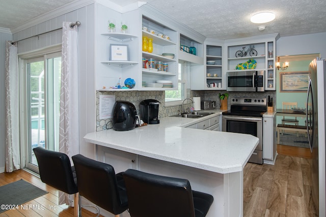 kitchen featuring appliances with stainless steel finishes, kitchen peninsula, a breakfast bar area, light wood-type flooring, and sink