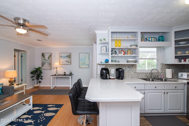 kitchen featuring ceiling fan, sink, tasteful backsplash, dark wood-type flooring, and a kitchen bar