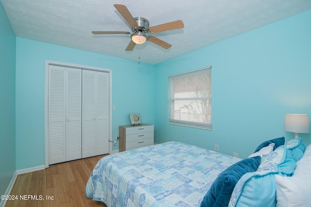 bedroom featuring a closet, light wood-type flooring, ceiling fan, and a textured ceiling