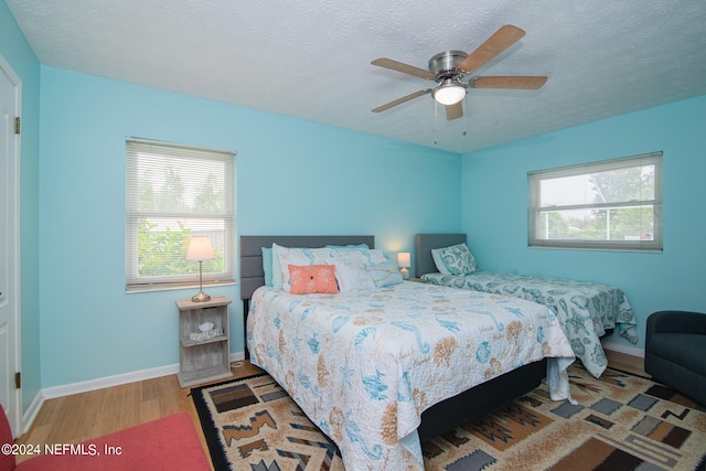 bedroom featuring wood-type flooring, ceiling fan, and a textured ceiling