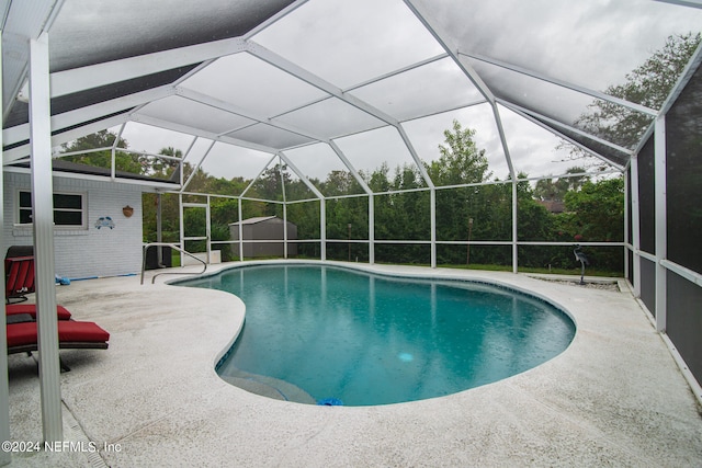 view of pool with a lanai, a patio, and a storage shed