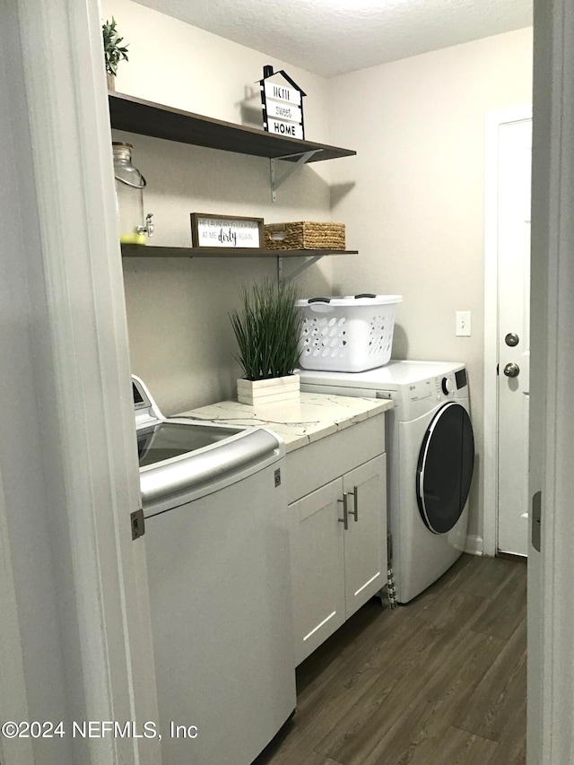 washroom with cabinets, a textured ceiling, dark wood-type flooring, and washing machine and dryer