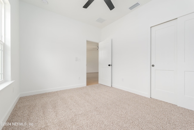 unfurnished bedroom featuring carpet, ceiling fan, and a closet