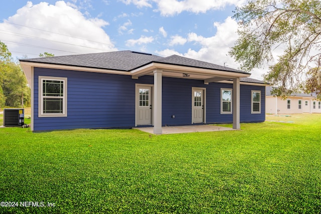 back of house featuring central air condition unit and a lawn