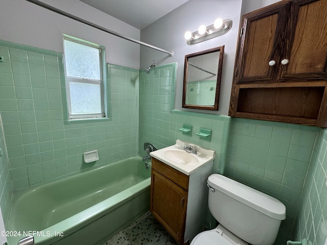 full bathroom with tile walls, vanity, toilet, and tiled shower / bath