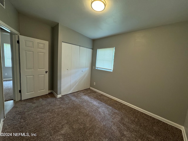 unfurnished bedroom with a closet, multiple windows, and carpet flooring