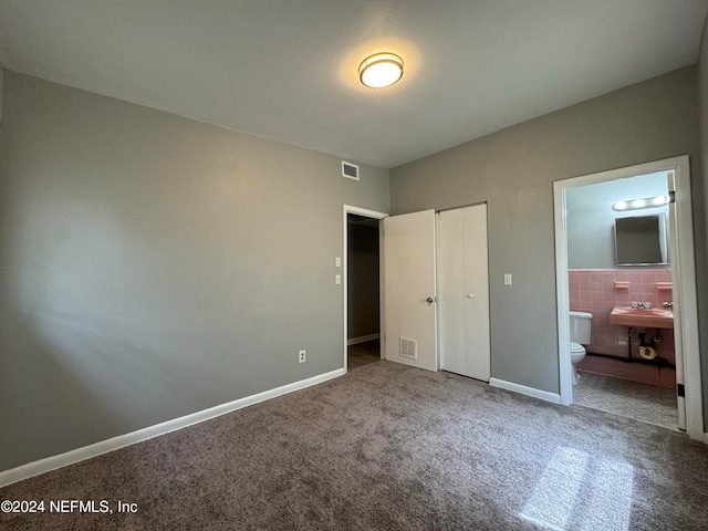 unfurnished bedroom with connected bathroom, carpet, and sink