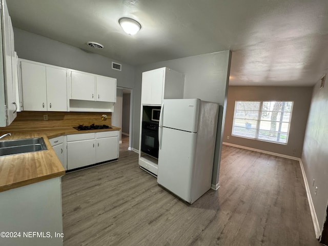 kitchen featuring sink, light wood-type flooring, white cabinetry, and black appliances