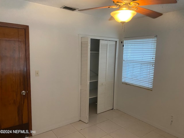 unfurnished bedroom with a closet, ceiling fan, and light tile patterned floors