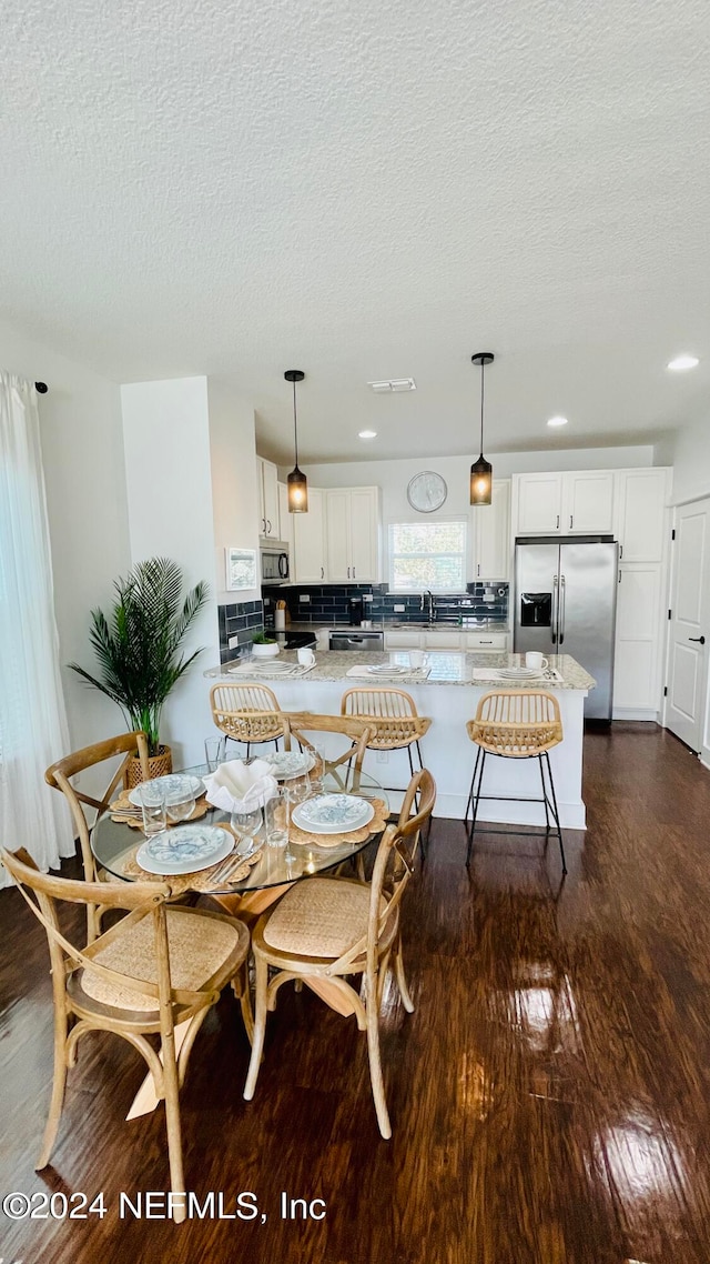 dining room with a textured ceiling, dark hardwood / wood-style floors, and sink