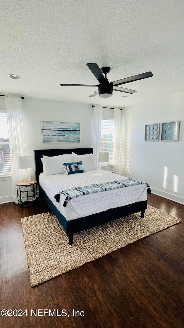 bedroom featuring dark wood-type flooring, a textured ceiling, and ceiling fan