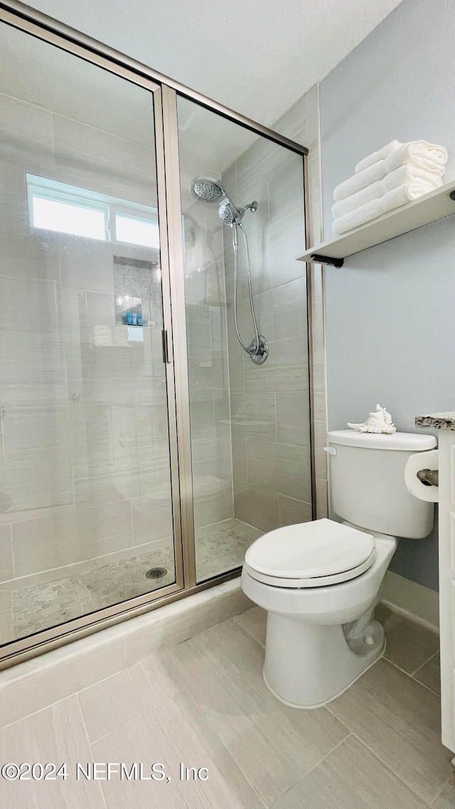 bathroom with toilet, tile patterned floors, and an enclosed shower