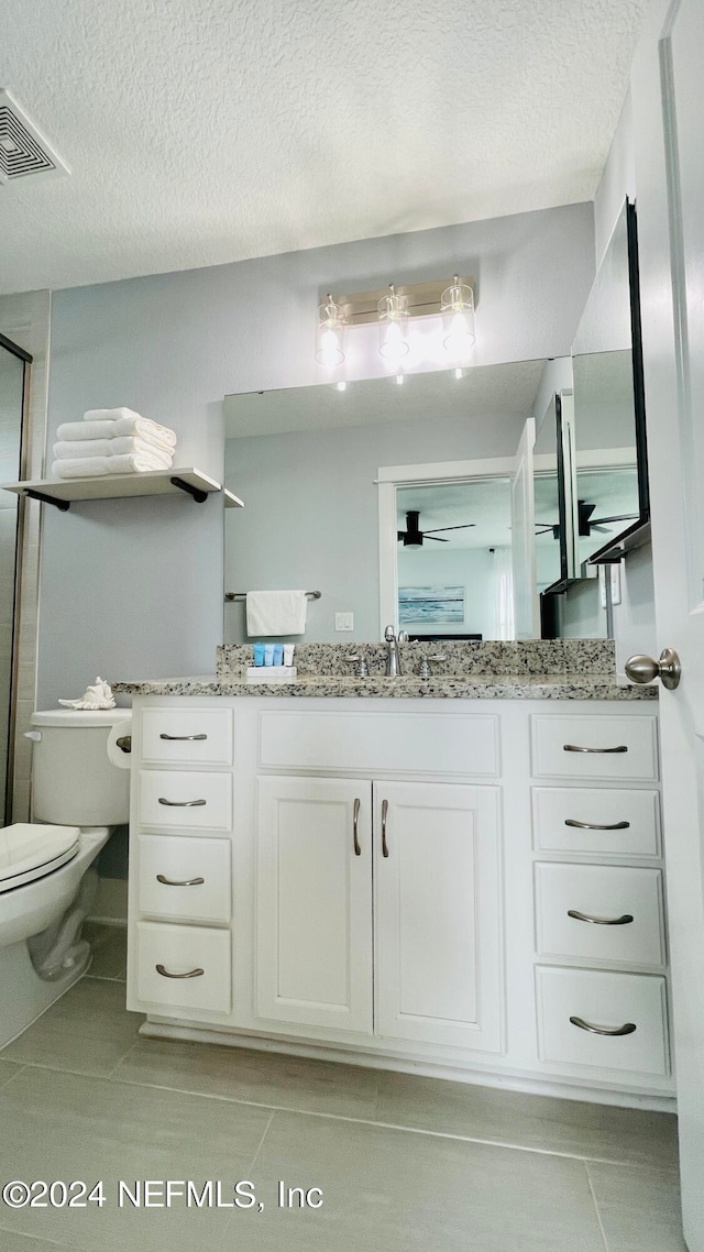 bathroom with ceiling fan, vanity, toilet, and a textured ceiling