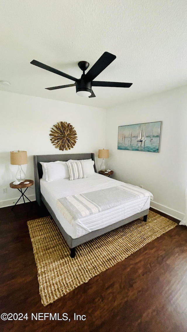 bedroom with ceiling fan, a textured ceiling, and dark wood-type flooring