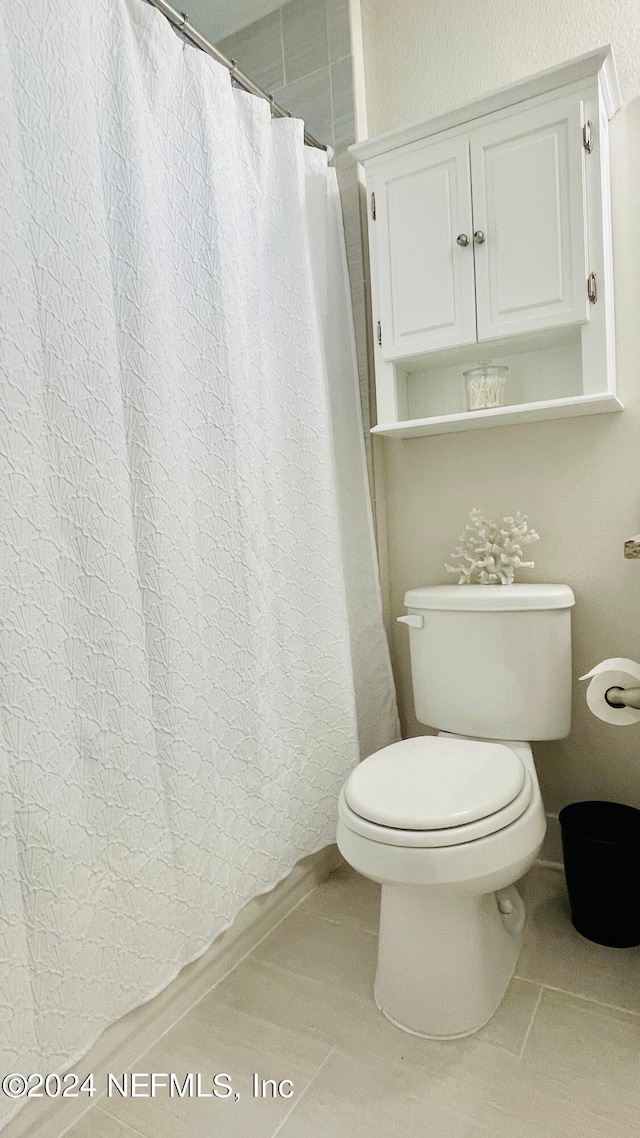 bathroom with curtained shower, tile patterned flooring, and toilet