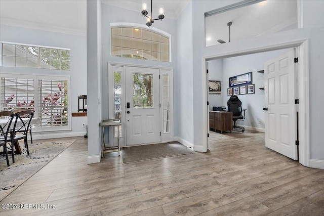 foyer entrance featuring a towering ceiling, plenty of natural light, and light hardwood / wood-style floors