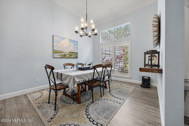 dining area with wood-type flooring, ornamental molding, an inviting chandelier, and a towering ceiling