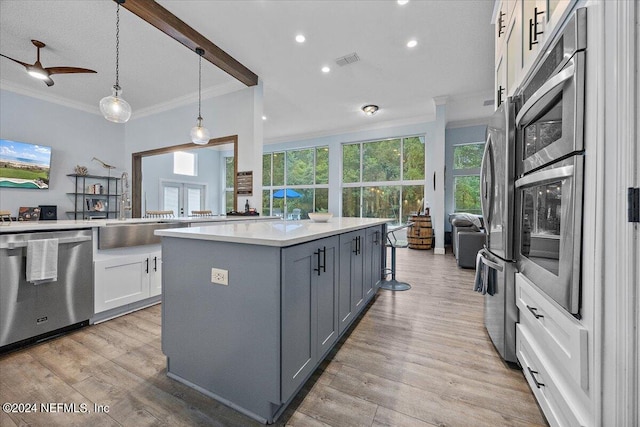 kitchen with ceiling fan, a kitchen island, decorative light fixtures, white cabinetry, and appliances with stainless steel finishes