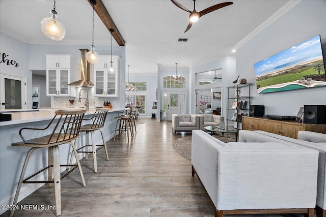 living room featuring a textured ceiling, hardwood / wood-style flooring, sink, ornamental molding, and ceiling fan