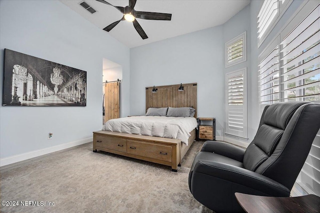 bedroom featuring ceiling fan and a barn door