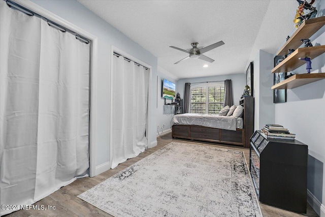 bedroom with a textured ceiling, ceiling fan, and hardwood / wood-style flooring