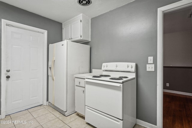 kitchen with white appliances, light tile patterned flooring, and white cabinets