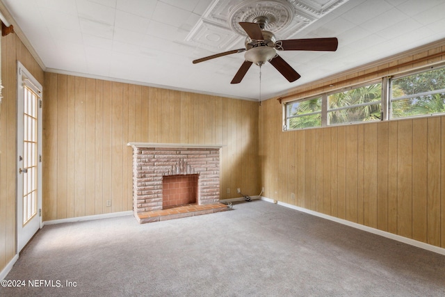 unfurnished living room featuring ceiling fan, wooden walls, a fireplace, and carpet