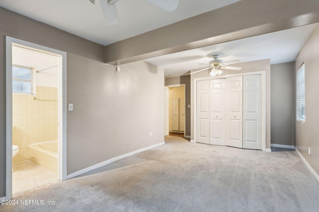 unfurnished bedroom featuring ceiling fan, light colored carpet, a closet, and connected bathroom