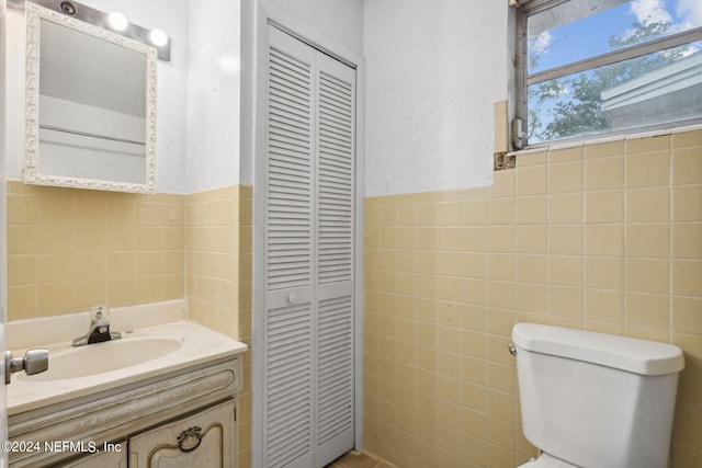 bathroom featuring vanity, tile walls, and toilet