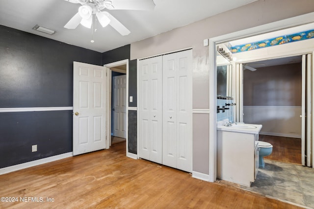 unfurnished bedroom featuring connected bathroom, light hardwood / wood-style floors, sink, and ceiling fan