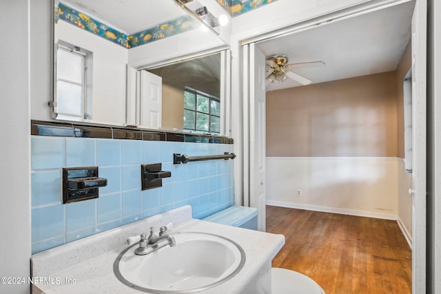 bathroom featuring wood-type flooring, decorative backsplash, ceiling fan, vanity, and toilet