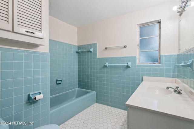 full bathroom featuring tile walls, tiled shower / bath, vanity, and toilet