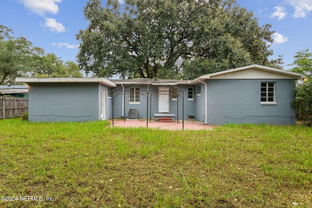 rear view of property with a lawn, a patio, and central air condition unit