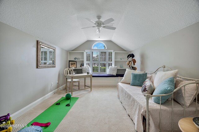 interior space with ceiling fan, built in features, a textured ceiling, carpet floors, and vaulted ceiling