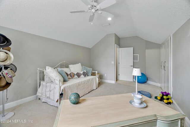 carpeted bedroom featuring a textured ceiling, vaulted ceiling, and ceiling fan