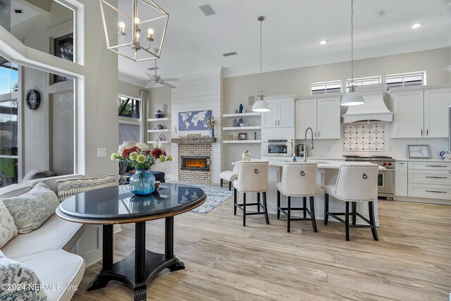 kitchen featuring pendant lighting, white cabinetry, appliances with stainless steel finishes, and custom range hood