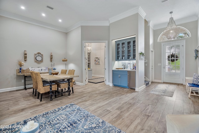 interior space with light wood-type flooring, crown molding, a high ceiling, and a chandelier