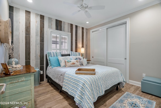 bedroom featuring a closet, light hardwood / wood-style floors, ceiling fan, and crown molding