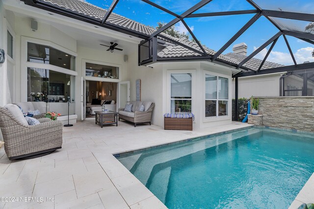 view of pool with outdoor lounge area, a lanai, a patio, and ceiling fan