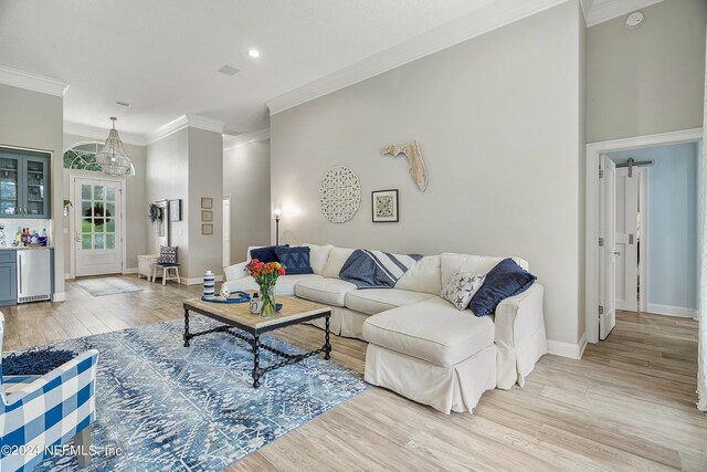 living room with wine cooler, crown molding, and light hardwood / wood-style floors