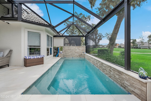 view of swimming pool featuring a lawn, glass enclosure, and a patio area