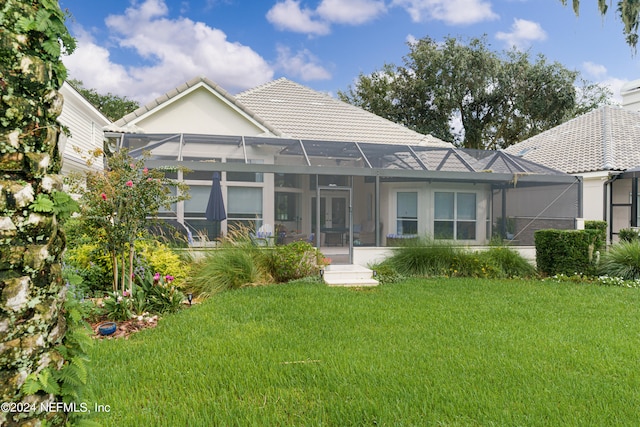 rear view of house with a lawn and glass enclosure