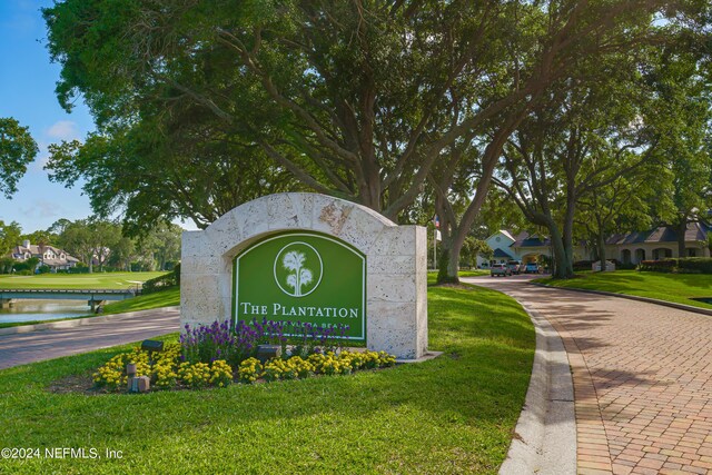 community sign with a lawn and a water view