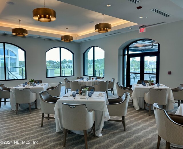 carpeted dining area with a raised ceiling and a wealth of natural light