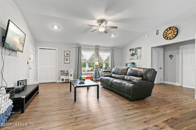 living room featuring ceiling fan, a textured ceiling, hardwood / wood-style floors, and vaulted ceiling