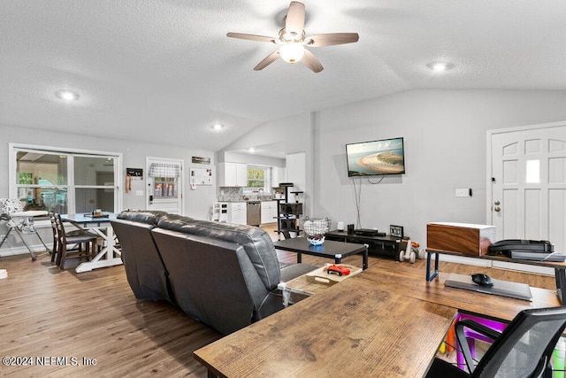 living room with a textured ceiling, lofted ceiling, hardwood / wood-style floors, and ceiling fan