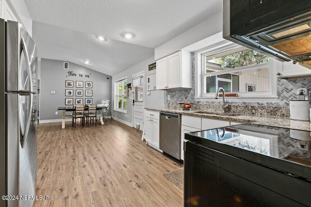 kitchen featuring tasteful backsplash, sink, vaulted ceiling, white cabinetry, and appliances with stainless steel finishes